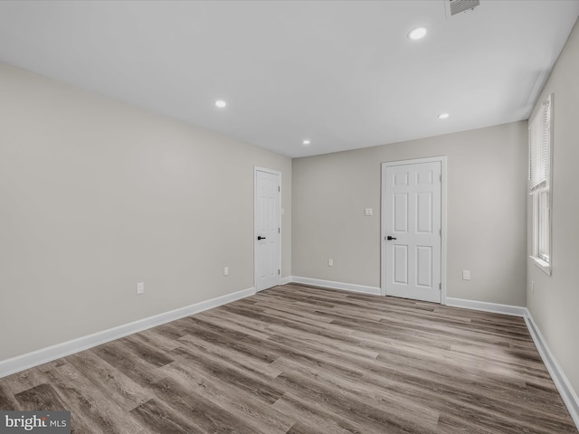 empty room featuring baseboards, recessed lighting, wood finished floors, and visible vents