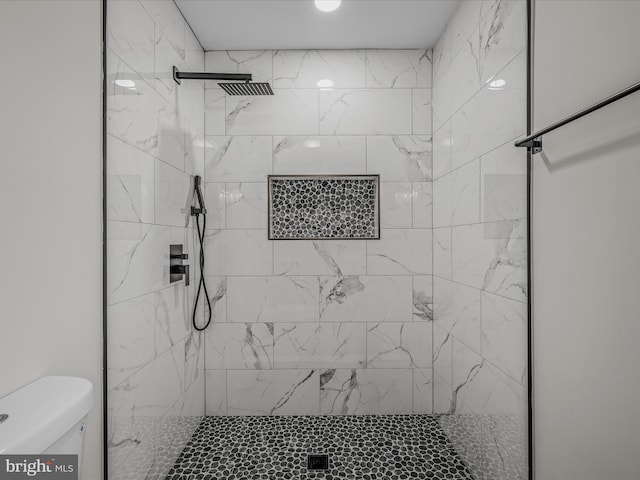 full bathroom featuring a tile shower and toilet