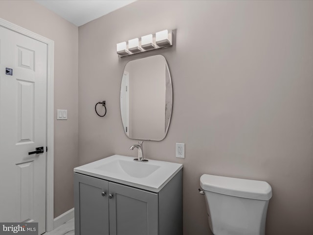half bathroom featuring vanity, baseboards, and toilet