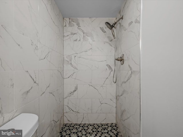 bathroom featuring a tile shower and toilet