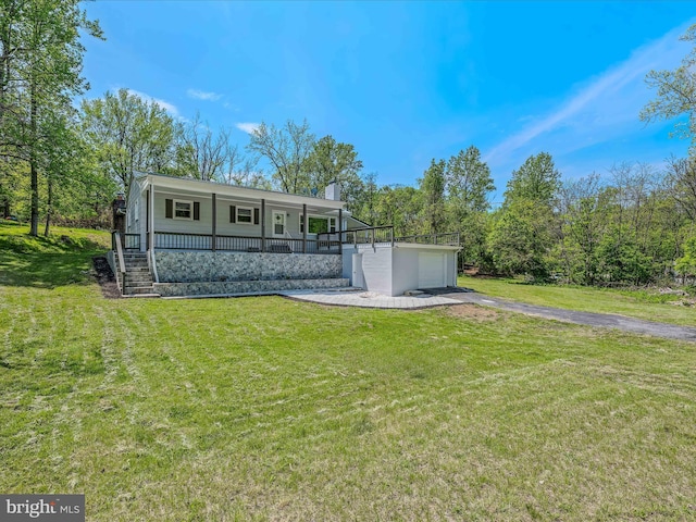 rear view of property featuring a porch, aphalt driveway, a lawn, and a chimney