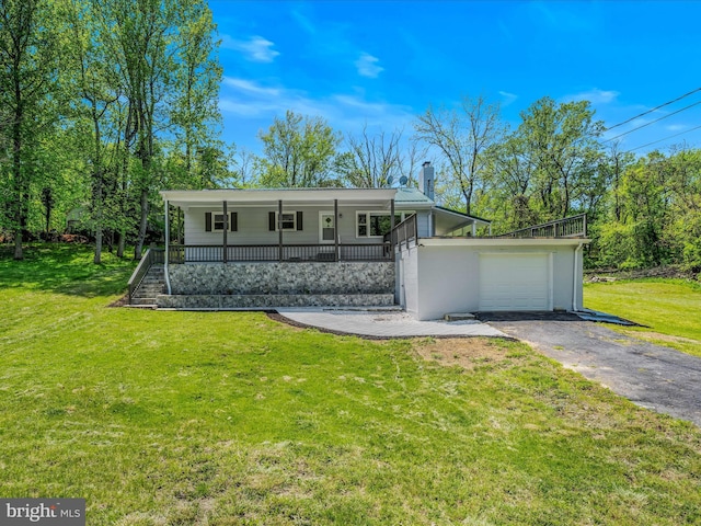 view of front of property with a chimney, a front yard, a porch, and aphalt driveway