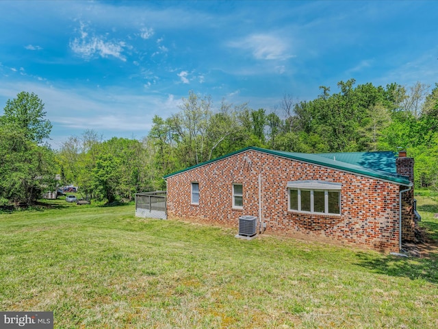 view of property exterior featuring a yard, brick siding, a chimney, and central air condition unit