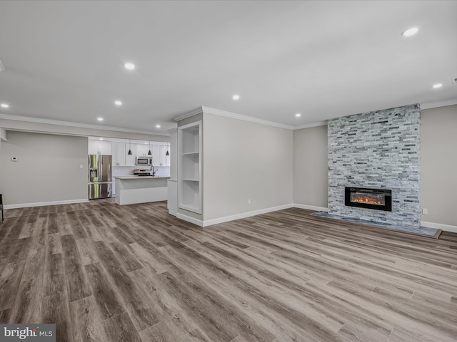 unfurnished living room with crown molding, recessed lighting, baseboards, and a fireplace