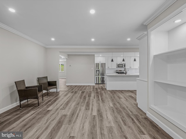 living room featuring crown molding, baseboards, and light wood-style floors