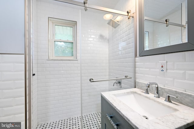 full bath featuring tile walls, tiled shower, and vanity