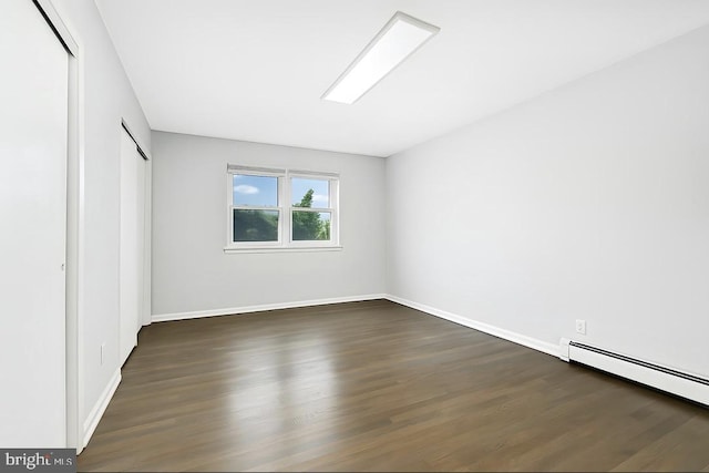 unfurnished bedroom with baseboards, baseboard heating, a closet, and dark wood-style floors