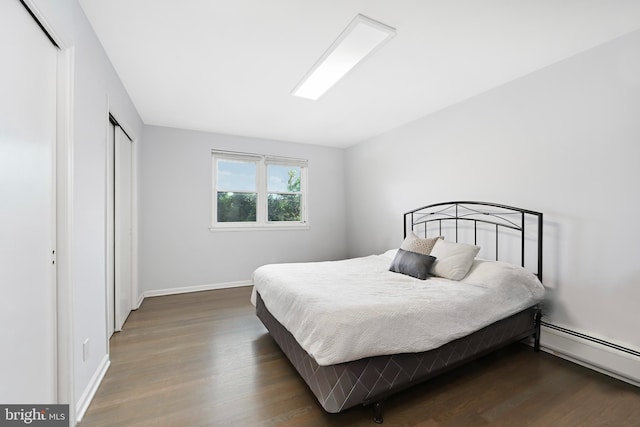 bedroom featuring a closet, baseboards, baseboard heating, and wood finished floors