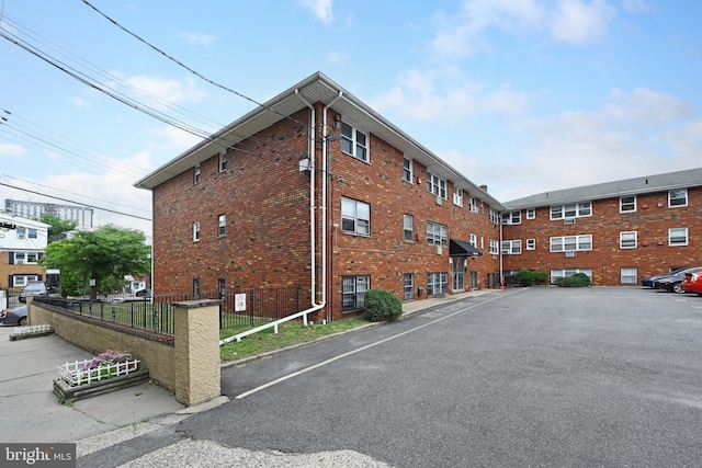 view of building exterior featuring fence and uncovered parking