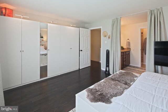 bedroom featuring ensuite bathroom and dark wood-style floors