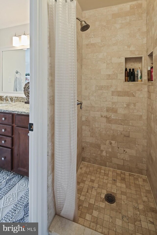 bathroom featuring tiled shower and vanity