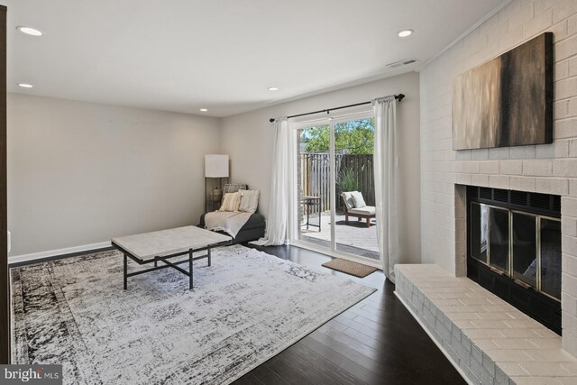 living area featuring a brick fireplace, recessed lighting, visible vents, and dark wood finished floors