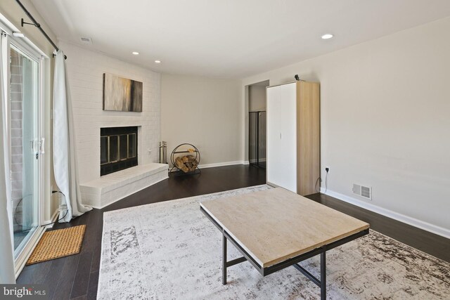 living room featuring baseboards, a fireplace, wood finished floors, and visible vents