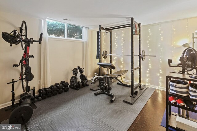 exercise area with baseboards, wood finished floors, and visible vents