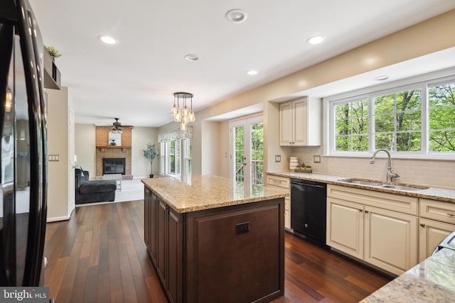 kitchen featuring a brick fireplace, decorative backsplash, a sink, and black appliances
