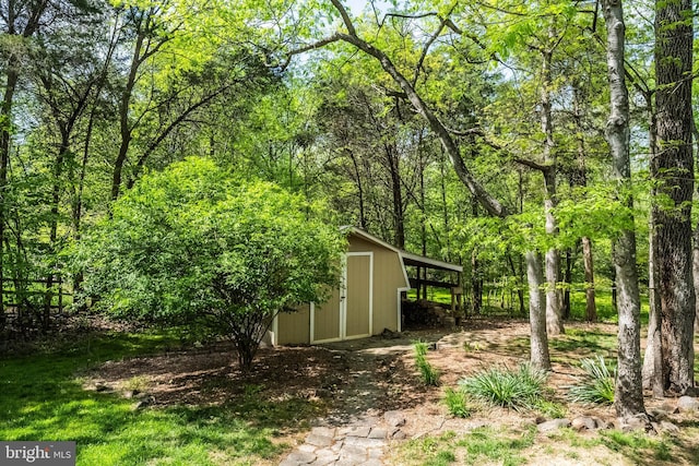 view of yard with a storage shed, an outbuilding, and a wooded view