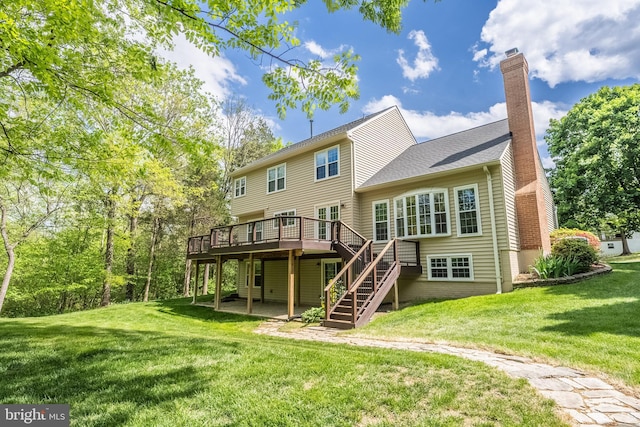 rear view of property with a chimney, a lawn, a wooden deck, a patio area, and stairs