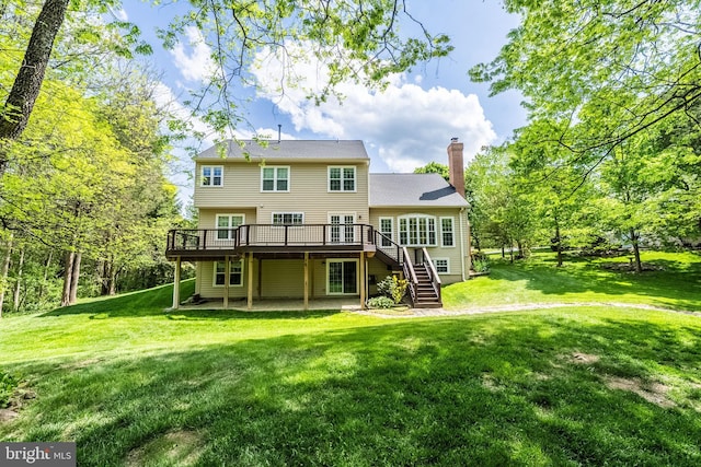 rear view of property featuring a lawn, a wooden deck, stairs, and a chimney