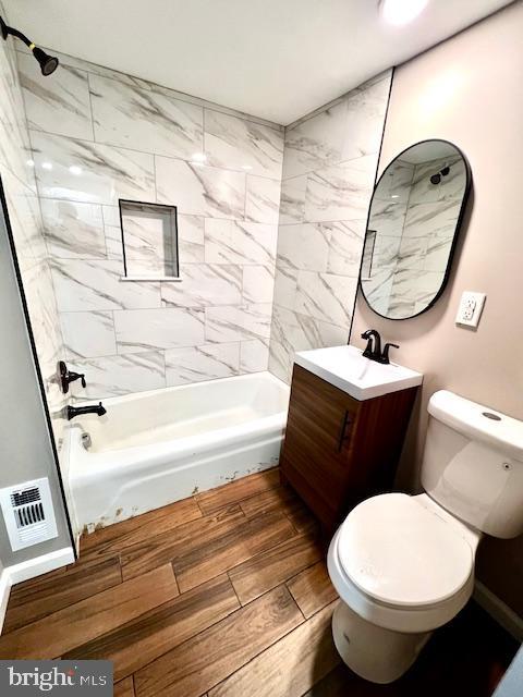 218 Cooper St, Beverly, NJ 08010 - bathroom featuring washtub / shower combination, vanity, toilet, and wood finished floors