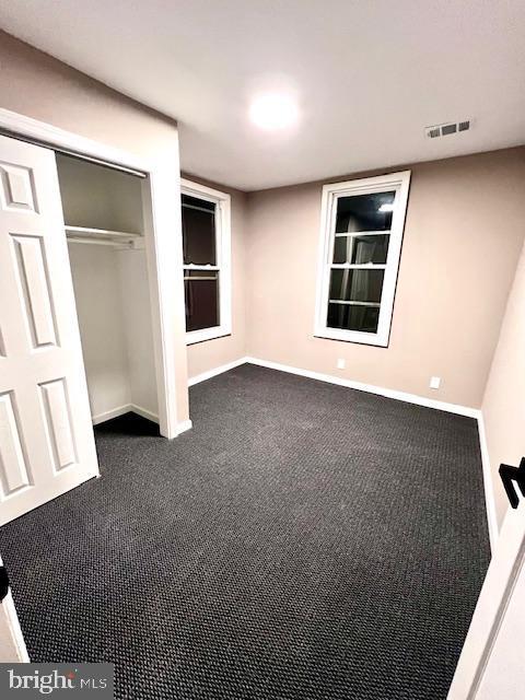 218 Cooper St, Beverly, NJ 08010 - unfurnished bedroom with baseboards, visible vents, dark carpet, and a closet