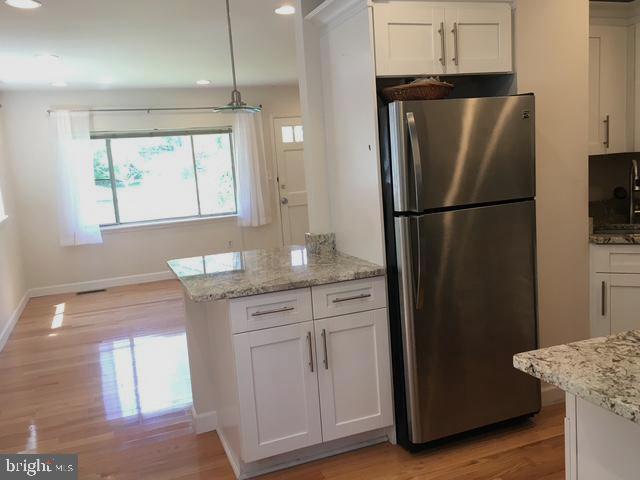 13211 Lutes Dr, Silver Spring, MD 20906 - kitchen with freestanding refrigerator, white cabinetry, light wood-style floors, baseboards, and recessed lighting