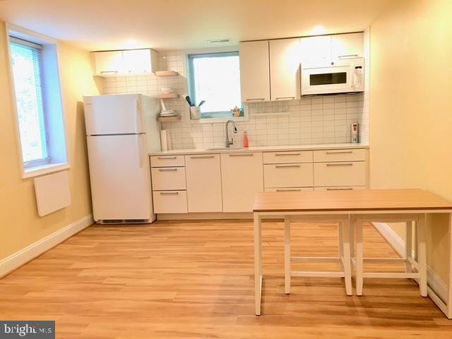 13211 Lutes Dr, Silver Spring, MD 20906 - kitchen with white appliances, a sink, light wood-type flooring, baseboards, and white cabinets