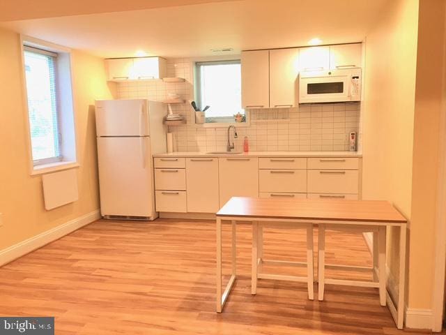 13211 Lutes Dr, Silver Spring, MD 20906 - kitchen with white appliances, baseboards, a sink, light wood-style floors, and white cabinets