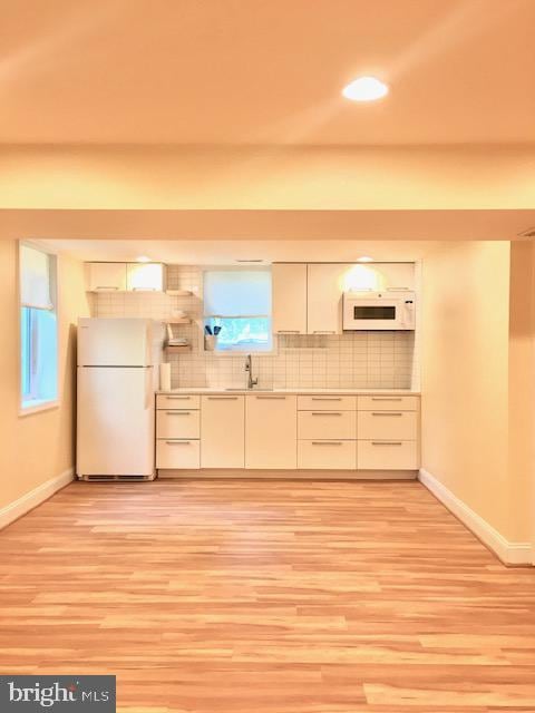 13211 Lutes Dr, Silver Spring, MD 20906 - kitchen featuring white appliances, baseboards, tasteful backsplash, light wood-type flooring, and a sink