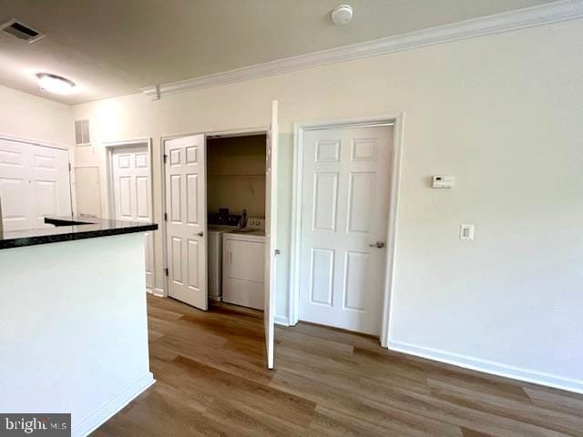 interior space with visible vents, ornamental molding, dark wood-type flooring, and washing machine and clothes dryer