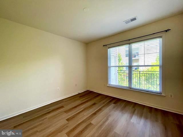 empty room with baseboards, visible vents, and wood finished floors