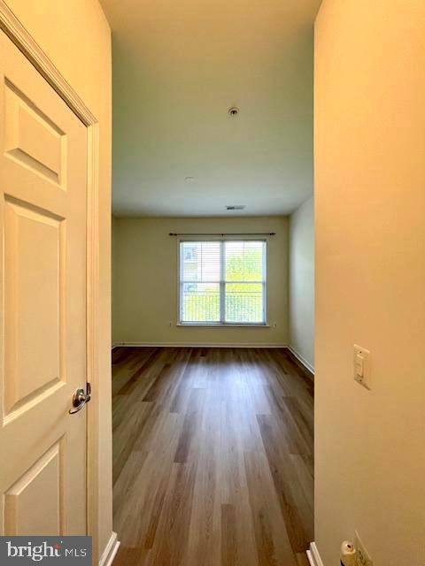 spare room with baseboards and wood finished floors