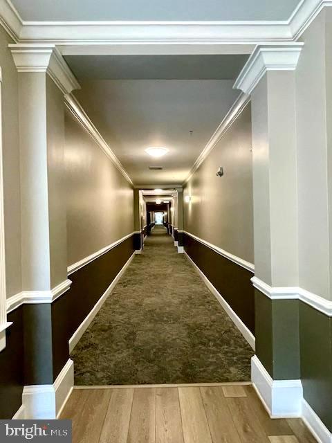 hallway with baseboards, ornamental molding, decorative columns, and wood finished floors
