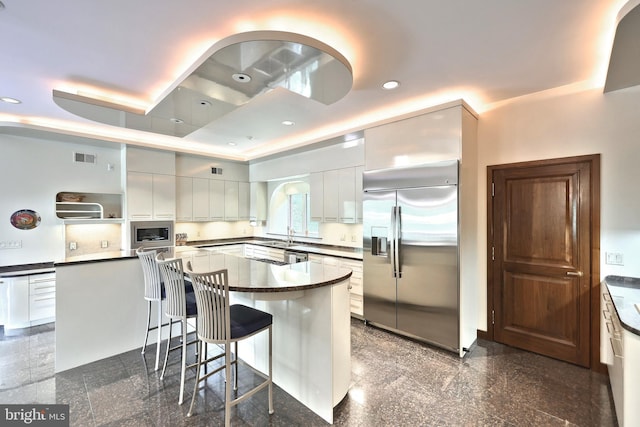 174 Springhouse Ln, Spring Grove, PA 17362 - kitchen with built in appliances, dark countertops, granite floors, a kitchen breakfast bar, and a raised ceiling