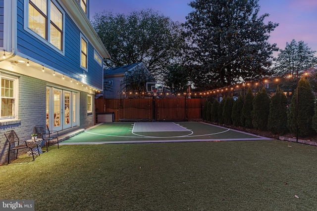 view of sport court with a fenced backyard, a yard, and basketball court