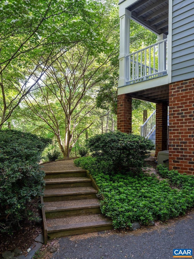 view of side of home featuring stairway, brick siding, and cooling unit