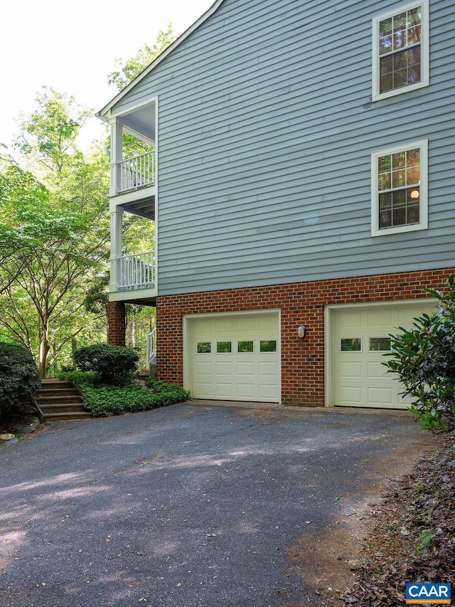 view of home's exterior with an attached garage, aphalt driveway, and brick siding