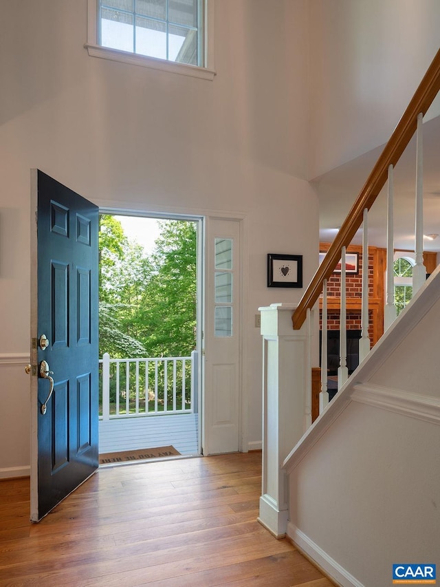 foyer entrance with baseboards, a towering ceiling, wood finished floors, and stairway