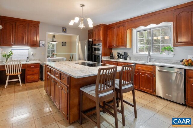 kitchen featuring pendant lighting, a center island, a sink, appliances with stainless steel finishes, and light tile patterned floors