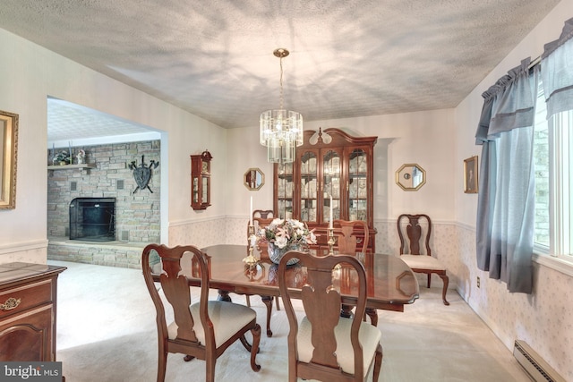 dining space featuring an inviting chandelier, light carpet, baseboard heating, wallpapered walls, and a wainscoted wall