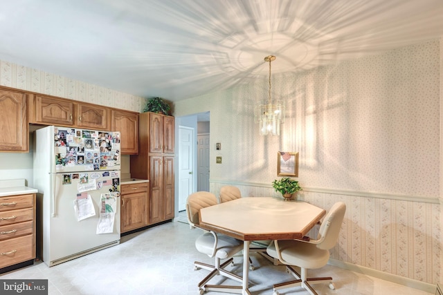 dining space featuring a chandelier and wallpapered walls