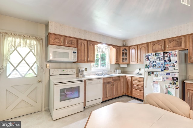 kitchen with a sink, wallpapered walls, white appliances, and visible vents