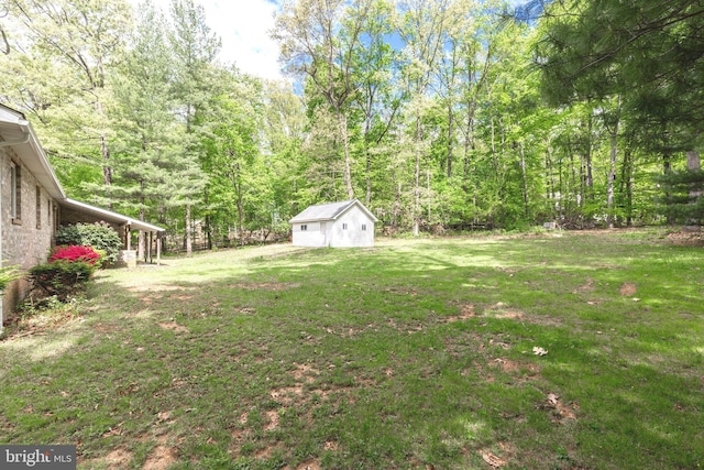 view of yard featuring a wooded view and an outbuilding