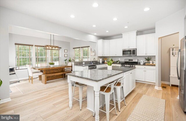 kitchen with a center island, white cabinets, stainless steel appliances, recessed lighting, and light wood-style flooring