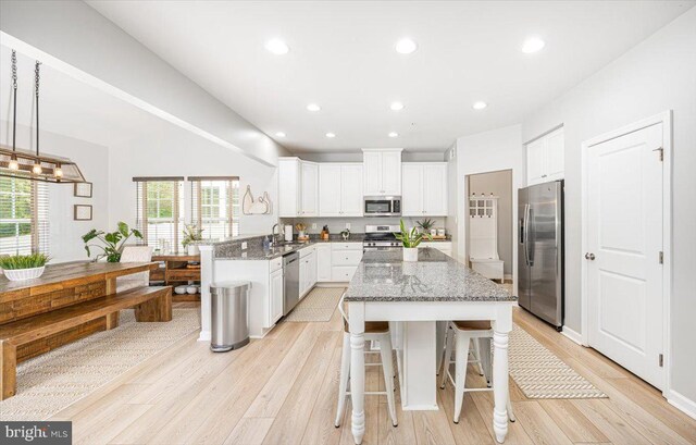 kitchen with light wood finished floors, white cabinets, stone counters, and stainless steel appliances