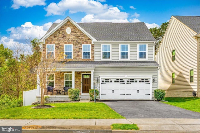 view of front of house with a porch, an attached garage, driveway, and a front yard