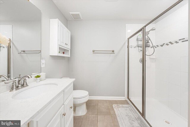full bathroom featuring vanity, a stall shower, toilet, and visible vents
