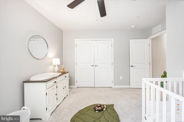 bedroom featuring light colored carpet, baseboards, visible vents, and a closet