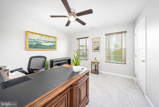 home office with baseboards, light carpet, a ceiling fan, and visible vents