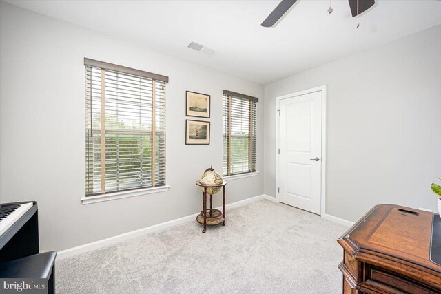 interior space with baseboards, a ceiling fan, and visible vents
