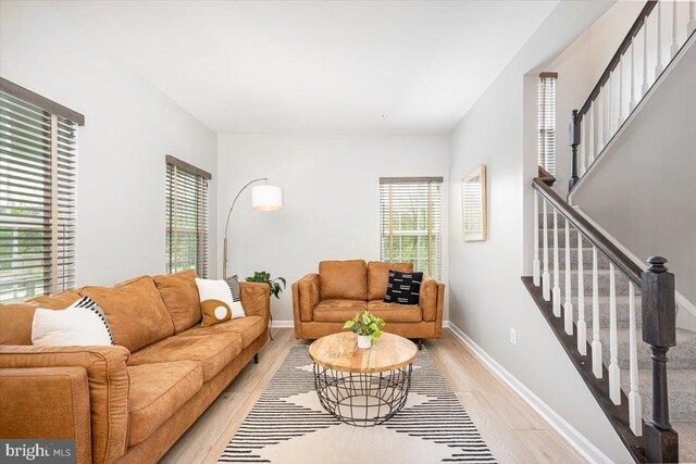 living area with stairs, baseboards, and light wood finished floors